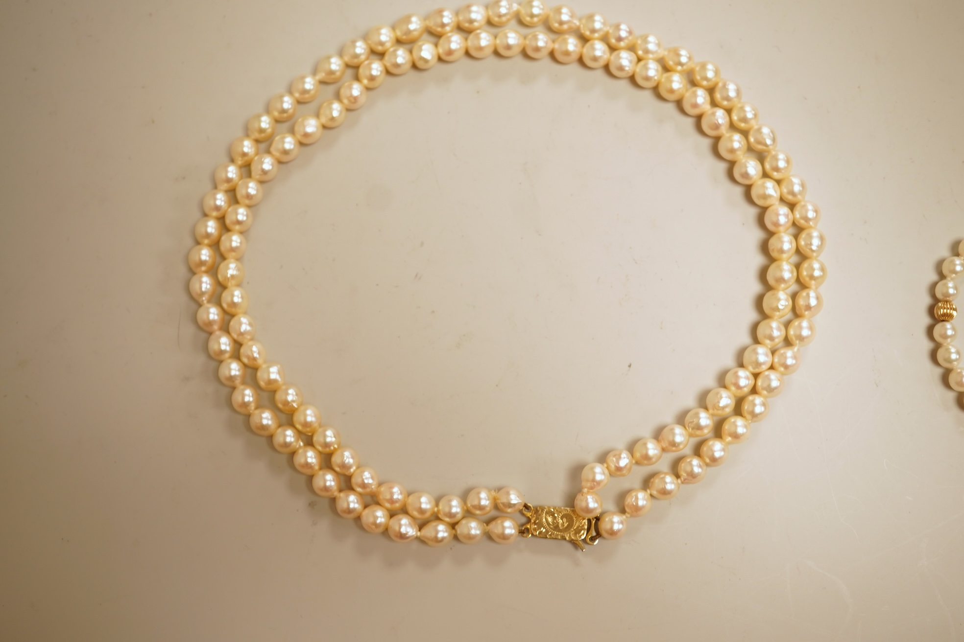 A modern twin strand cultured pearl choker necklace, with an engraved 9ct clasp, approx. 40cm, together with a cultured pearl bracelet, with diamond chip set butterfly shaped 14k clasp, 18cm, with four fluted yellow meta